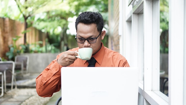 Empresarios que trabajan en computadoras tomando café y sonriendo