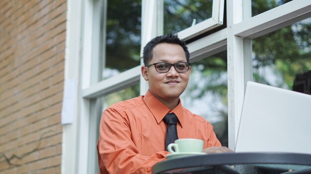 Empresarios que trabajan en computadoras tomando café y sonriendo