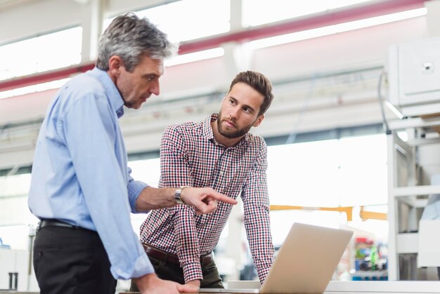 Empresarios que usan laptop en la sala de producción