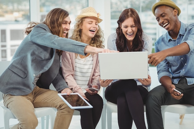 Empresários rindo enquanto aponta para o laptop