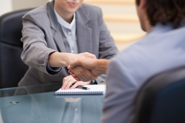 Foto empresarios sentados mientras se dan la mano