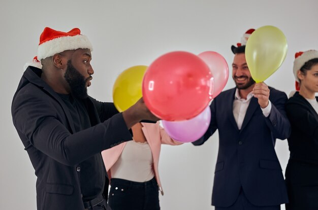 Los empresarios con sombrero de santa jugando con globos