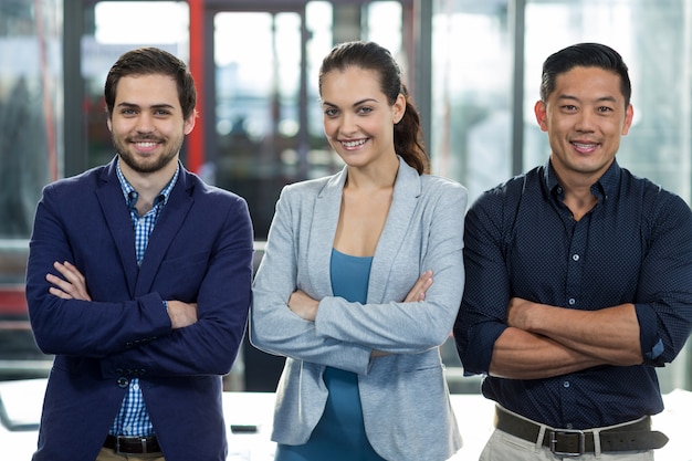 Empresarios sonrientes de pie con los brazos cruzados en la oficina