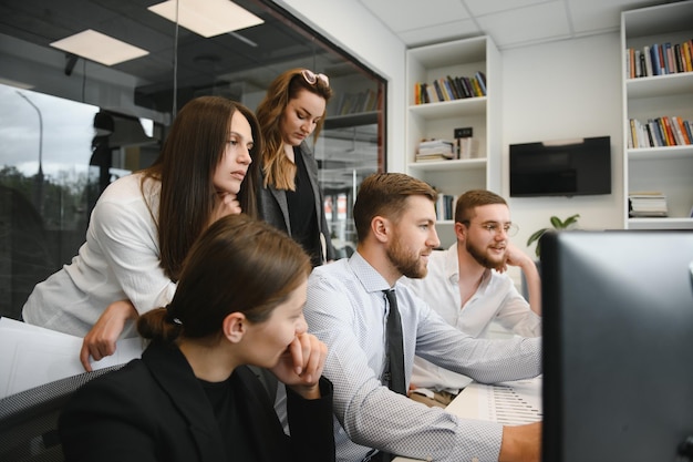 Empresarios sonrientes sentados en un escritorio frente a una computadora portátil