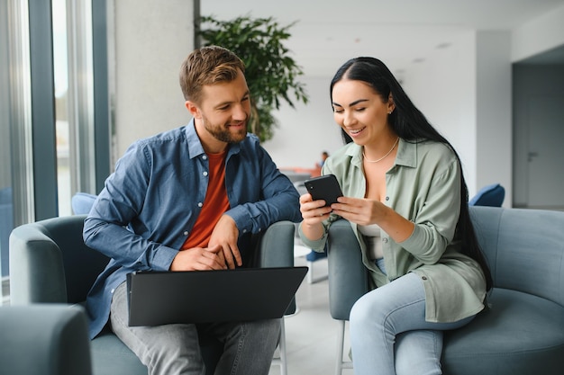 Empresários sorridentes trabalham colaboram no brainstorming do computador sobre a inicialização da empresa na reunião do escritório Colegas diversos motivados olham para a tela do laptop e discutem ideias de projetos de negócios juntos