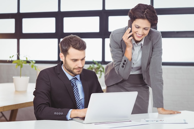 Empresarios con teléfono móvil y computadora portátil en la oficina