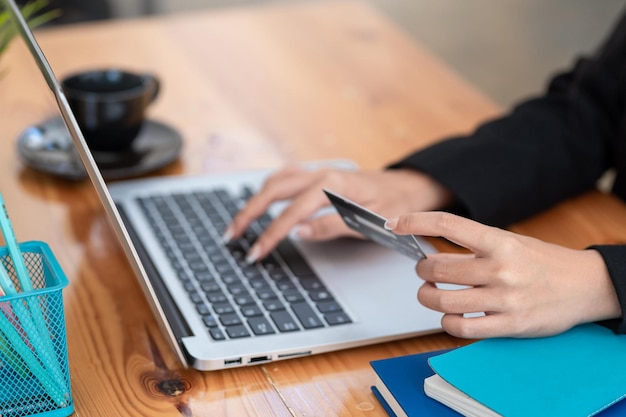 Los empresarios tienen tarjetas de crédito para comprar en línea en la computadora portátil de la oficina