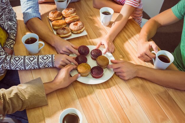 Foto empresarios tomando pasteles en la mesa