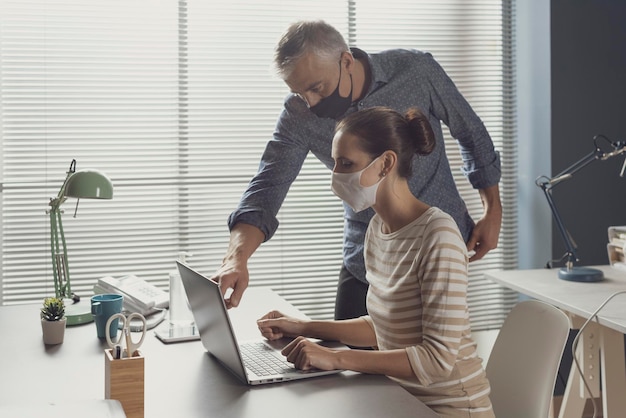 Empresarios trabajando juntos en la oficina y usando máscaras faciales