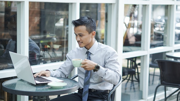 Empresários trabalhando em computadores tomando café e sorrindo