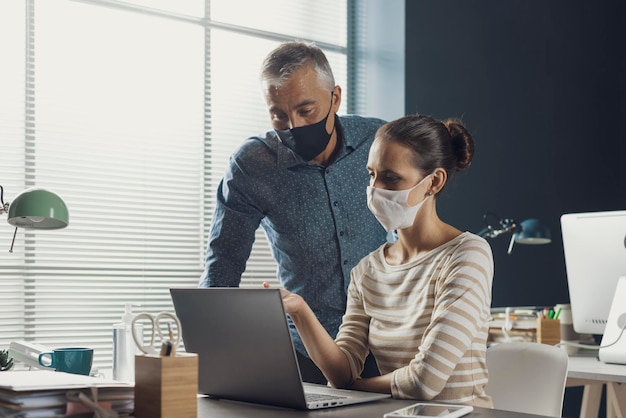 Empresários trabalhando juntos e usando máscaras faciais