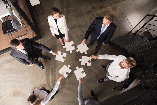 Foto empresários trabalhando juntos para construir um grande quebra-cabeça. conceito de trabalho em equipe, parceria, integração e startup.