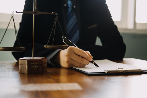 Empresas y abogados discutiendo documentos contractuales con una balanza de bronce en el escritorio de la oficina Servicios legales de asesoramiento jurídico Justicia y concepto de ley Imagen con efecto de grano de película