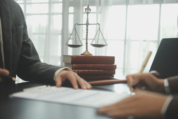 Empresas y abogados discutiendo documentos contractuales con una balanza de bronce en el escritorio de la oficina Servicios legales de asesoramiento jurídico Justicia y concepto de ley Imagen con efecto de grano de película