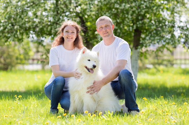 Enamorados están caminando con un perro en el campo.