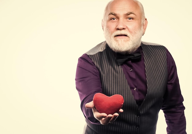 Enamórate Diagnóstico y tratamiento de latidos cardíacos Atención médica Prevención de ataques cardíacos Problemas cardíacos y atención médica Hombre mayor con cabeza calva y barba sostiene corazón rojo Hombre maduro con corazón de San Valentín