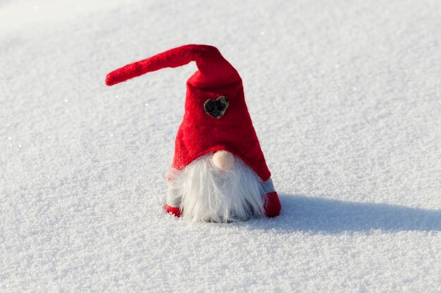 Un enano con un sombrero rojo en la nieve.