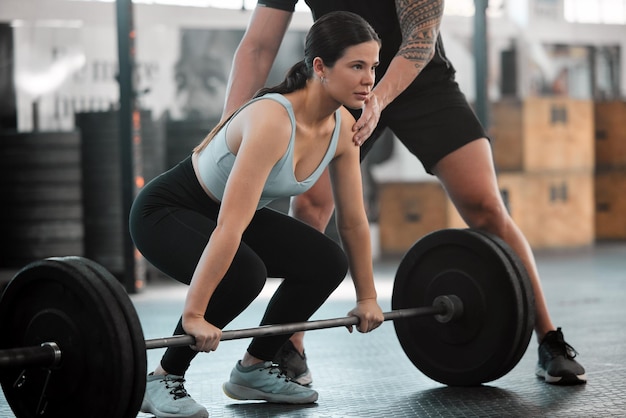 Encajar a una joven fuerte levantando pesas en el gimnasio Mujer atlética activa asistida por un entrenador de entrenamiento de apoyo Señora de ejercicio y fitness entrenando con entrenador de salud y bienestar en el interior