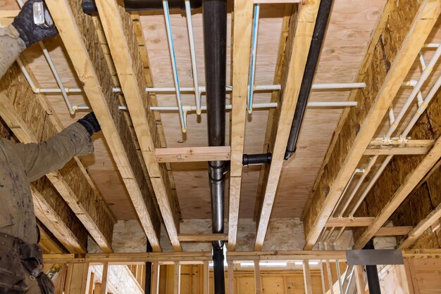 Encanador colando tubos de pvc de drenagem de esgoto na casa em construção o sistema de águas residuais