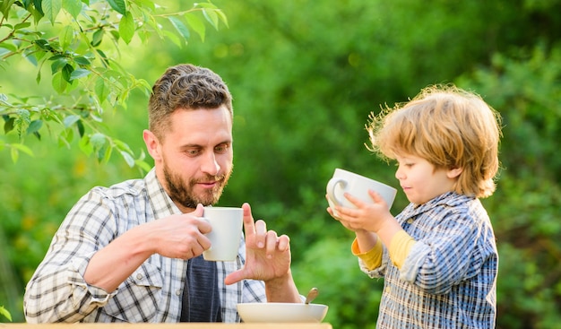 Les encanta comer juntos. Desayuno de fin de semana. padre e hijo comen al aire libre. niño pequeño con papá. comida sana. Vinculación del día de la familia. alimentos orgánicos y naturales. Familia feliz junta.