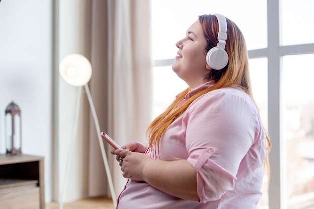 Encantado de agradable mujer sonriendo mientras disfruta de su música favorita en auriculares