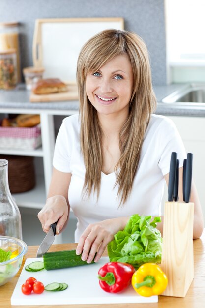 Encantado mujer prapring una ensalada en la cocina