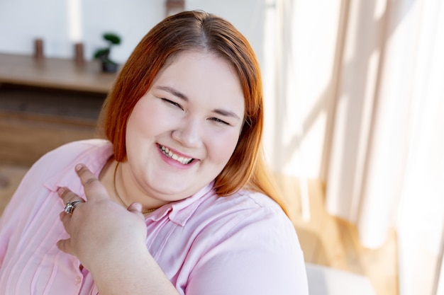 Encantado de mujer regordeta sonriendo mientras acepta su cuerpo