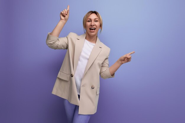 Encantador adulto joven rubia en chaqueta sonriendo sobre fondo de estudio