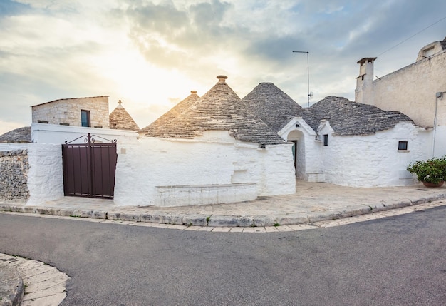 Encantador casco antiguo de Alberobello con casas Trulli entre plantas verdes y flores, principal distrito turístico, región de Apulia, sur de Italia. Edificios típicos construidos con muros de piedra seca y r cónica