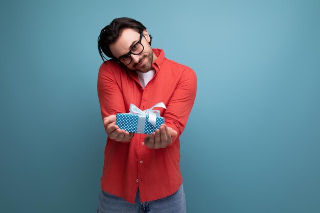 Foto encantador hombre positivo en una camisa roja adivina lindamente lo que se le presentó en una caja