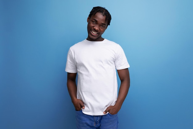 Encantador jovem africano com dreadlocks em camiseta branca com espaço em branco para o logotipo