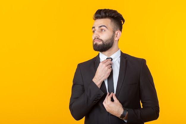 Encantador joven empresario seguro de sí mismo vistiendo ropa formal posando sobre un fondo amarillo