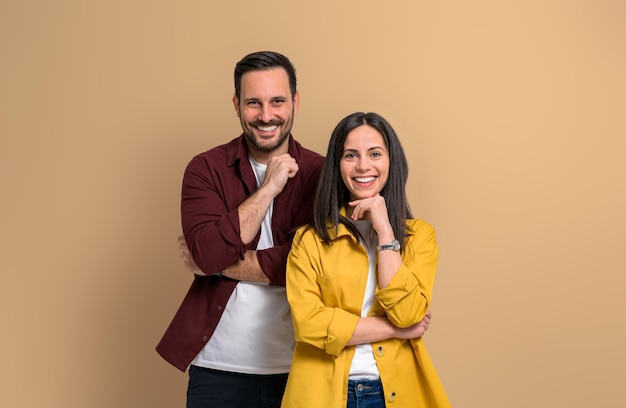 Encantador joven y mujer con las manos en la barbilla sonriendo y mirando a la cámara