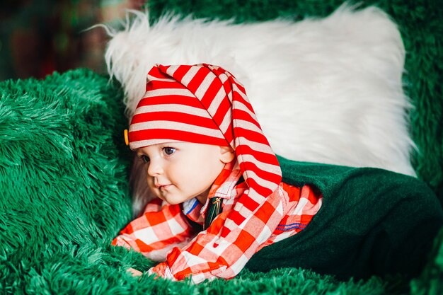 Encantador niño con camisa a cuadros roja y sombrero de Navidad