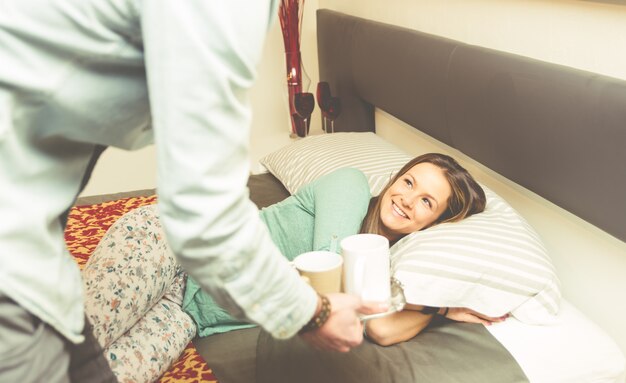 El encantador novio le trae el desayuno a su novia por la mañana.