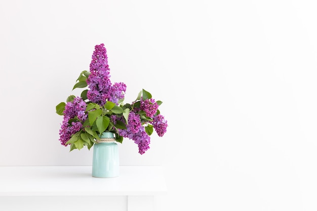 Encantador ramo de lilas florecientes en jarrón sobre gris