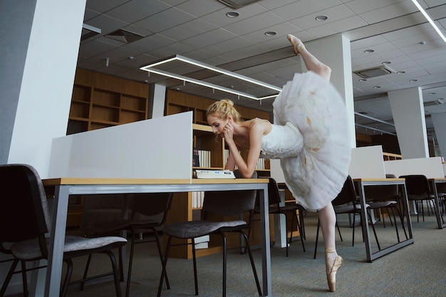 Encantadora bailarina foi à biblioteca escolher um novo livro durante um intervalo mostrando seu alongamento e flexibilidade