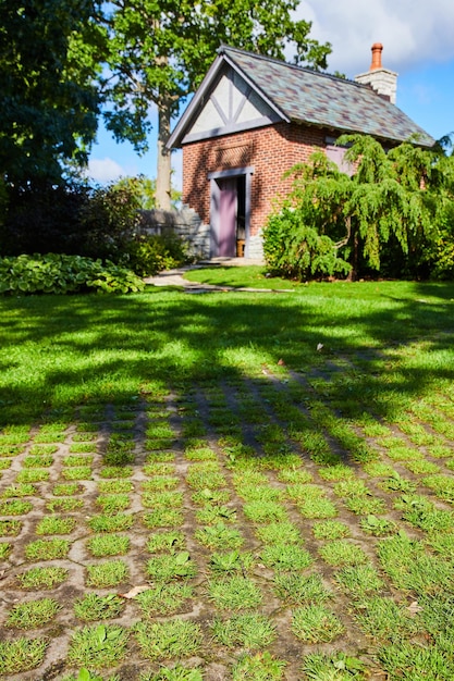 Foto encantadora cabaña de ladrillo con puerta púrpura y sendero de adoquines en exuberante vegetación