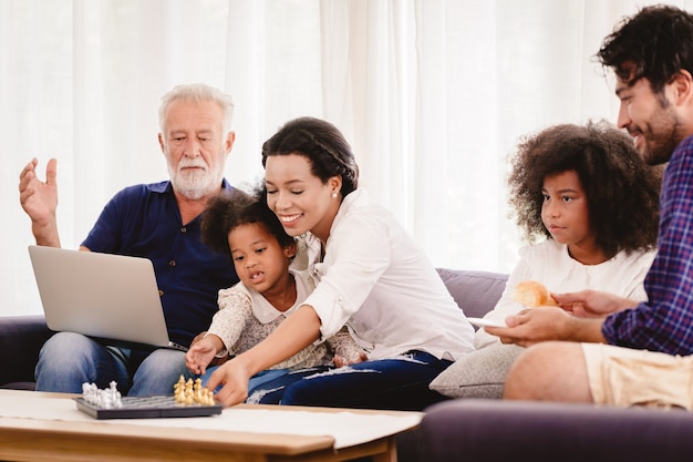 Encantadora casa familia feliz viviendo juntos en la sala de estar, padre, madre y abuelo jugando con la hija de la raza mixta