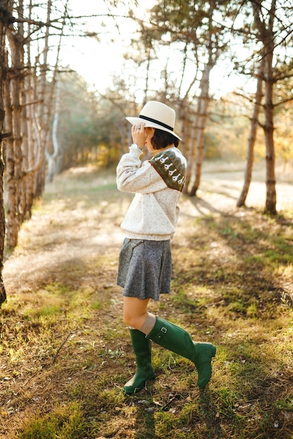 Encantadora chica con una hermosa sonrisa al atardecer en el bosque La chica está vestida con un sombrero