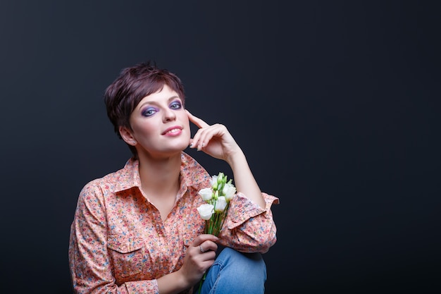 Encantadora chica sostiene flores sobre un fondo negro