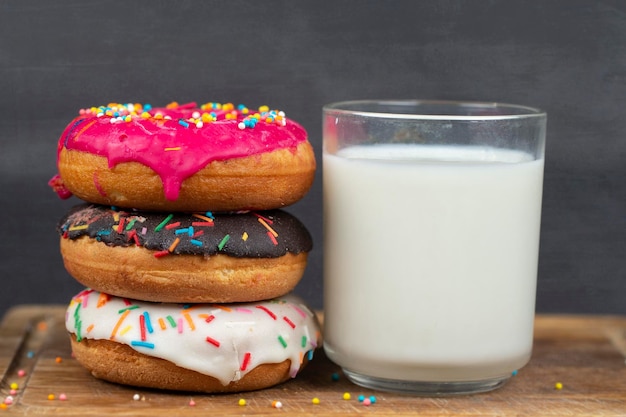 Encantadora comida dulce Pila de rosquillas variadas de colores glaseados con una taza de leche