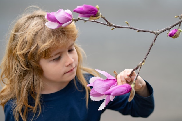 Encantadora criança loira no fundo das flores no verão Linda criança trabalhando no jardim criança cuidando de flores aproveitando o dia quente e ensolarado