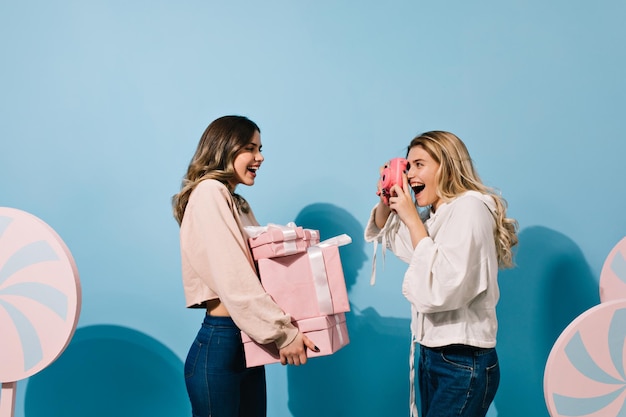 Encantadora cumpleañera posando para un amigo con cámara Foto de estudio de damas felices divirtiéndose en el evento