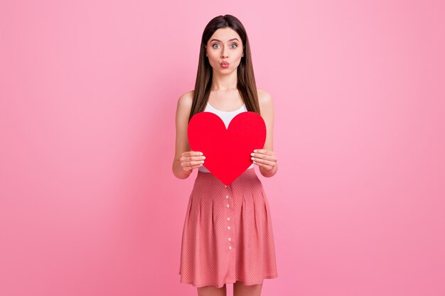 encantadora dama morena romántica sostenga tarjeta de corazón de papel rojo enviar beso al aire