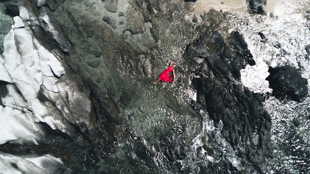 Encantadora dama tendida entre las rocas con un vestido rojo