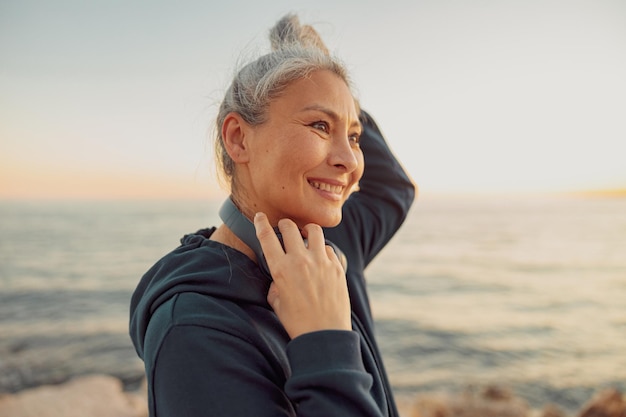 Encantadora deportista con auriculares de pie junto al mar