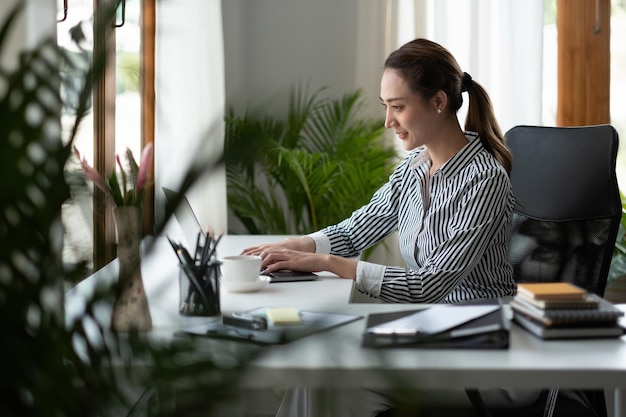 Encantadora empresária asiática trabalhando em laptop para contabilidade financeira no escritório