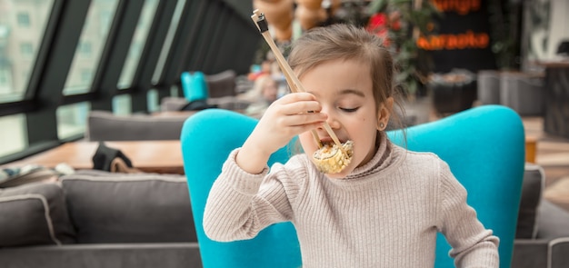 Encantadora engraçadinha comendo sushi em um restaurante