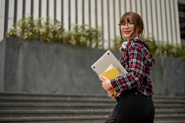 Encantadora estudante asiática subindo as escadas do lado de fora do prédio do campus